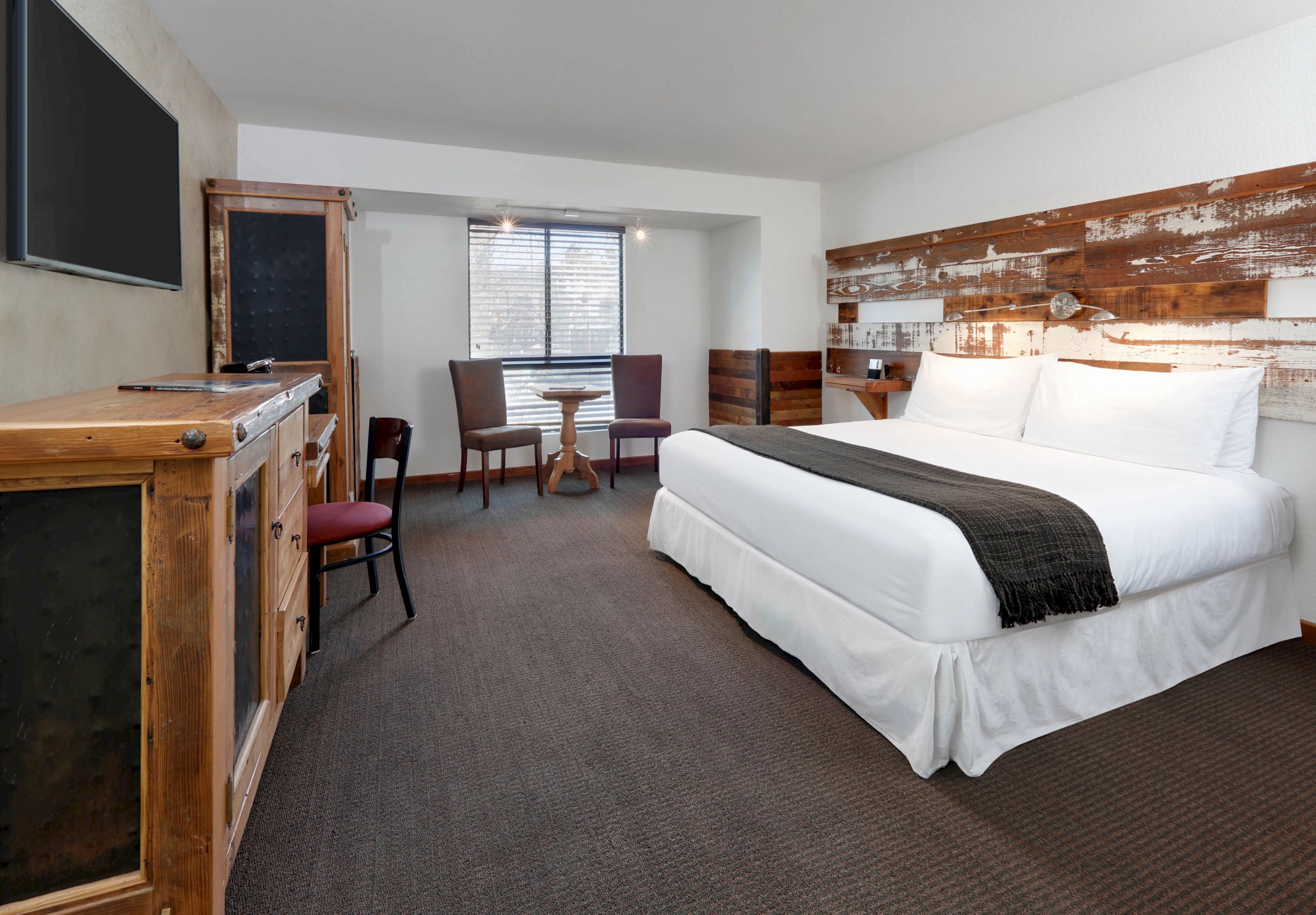A hotel room with a large bed, wooden furniture, and a window.